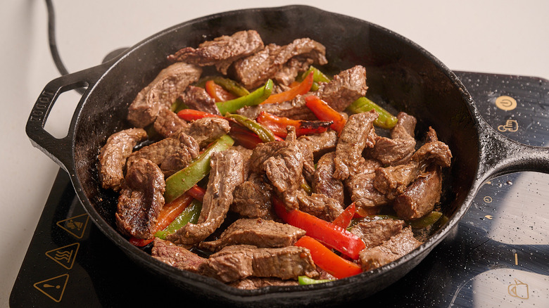 cooking steak and peppers in a skillet