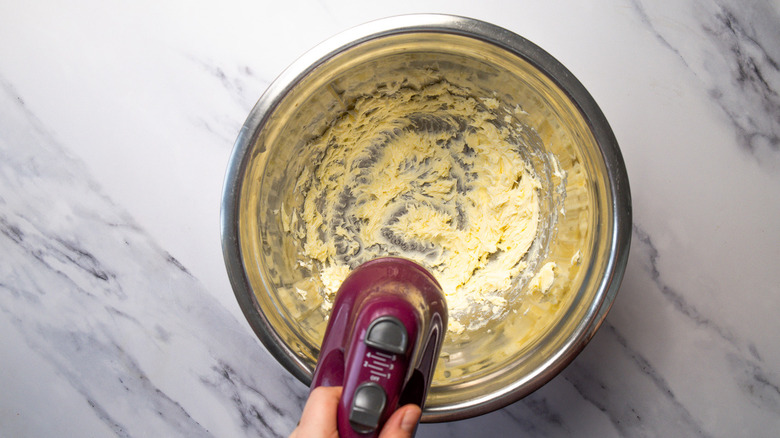 Beating butter in metal bowl with handheld mixer