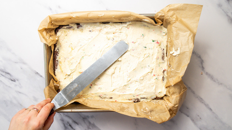 Spreading buttercream on peppermint bark cookie bars
