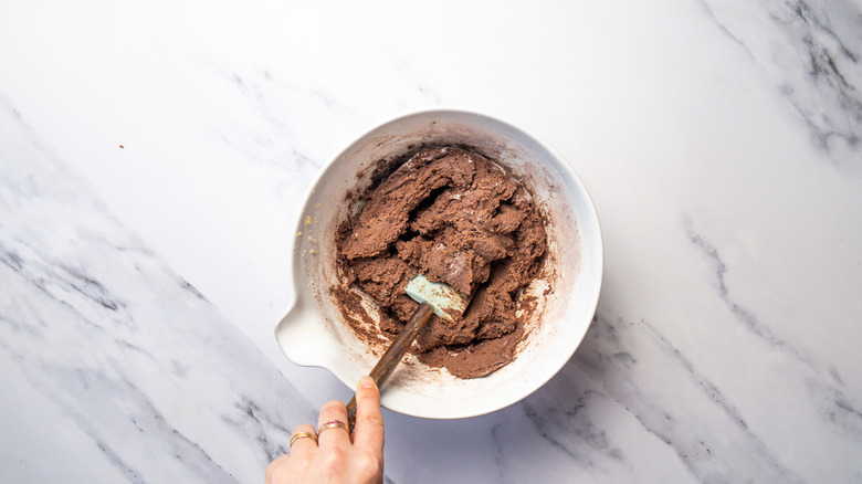 Mixing chocolate brownie dough in bowl with spatula