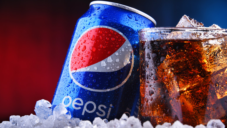 A can of pepsi with a glass of ice 