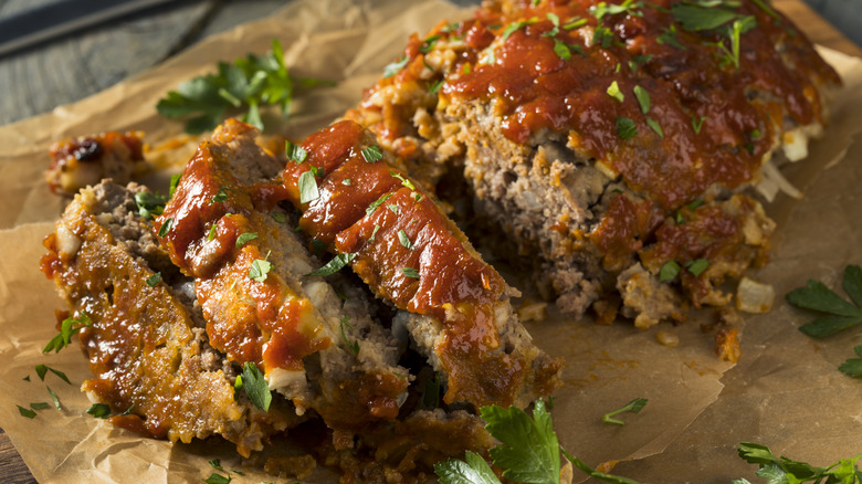 Sliced meatloaf covered in herbs and sauce