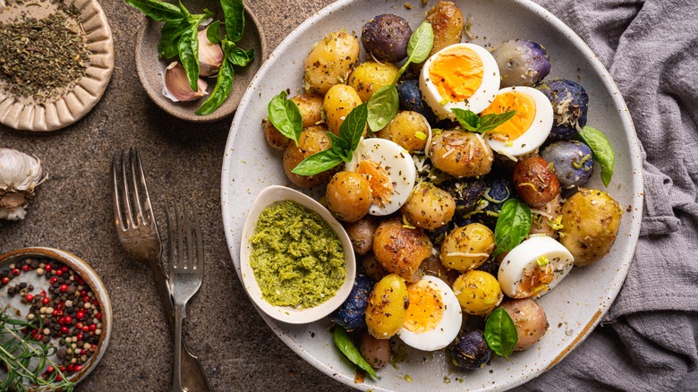 Chunky potato, jammy egg, and pesto salad with bowls of ingredients