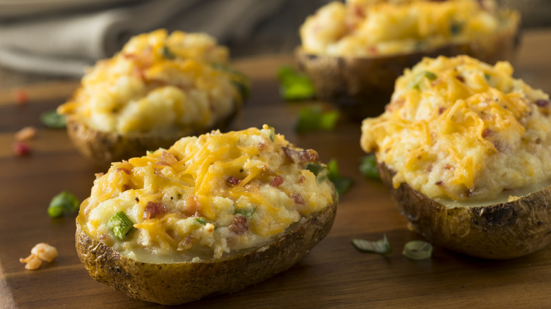 Loaded baked potatoes on a chopping board
