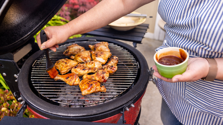A person grilling BBQ chicken