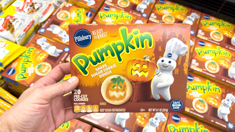 A hand holding up a package of Pillsbury pumpkin ready to bake cookies