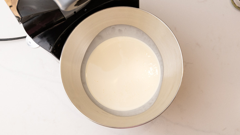 Aerial view of heavy cream in a stand mixer bowl on marble surface