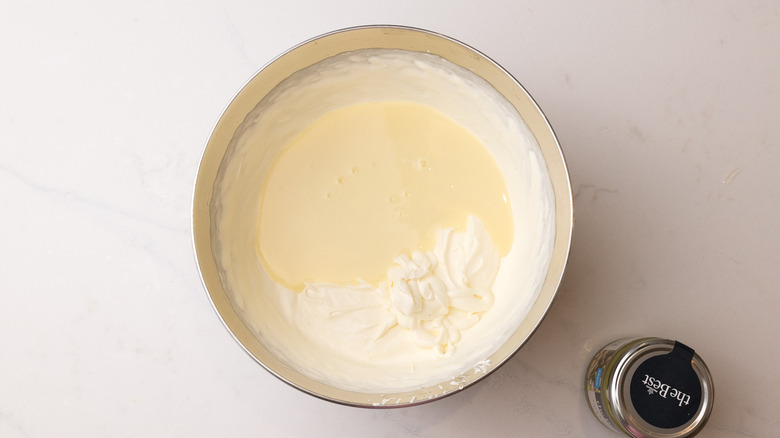 Aerial view of mixing bowl containing condensed milk and softly whipped cream