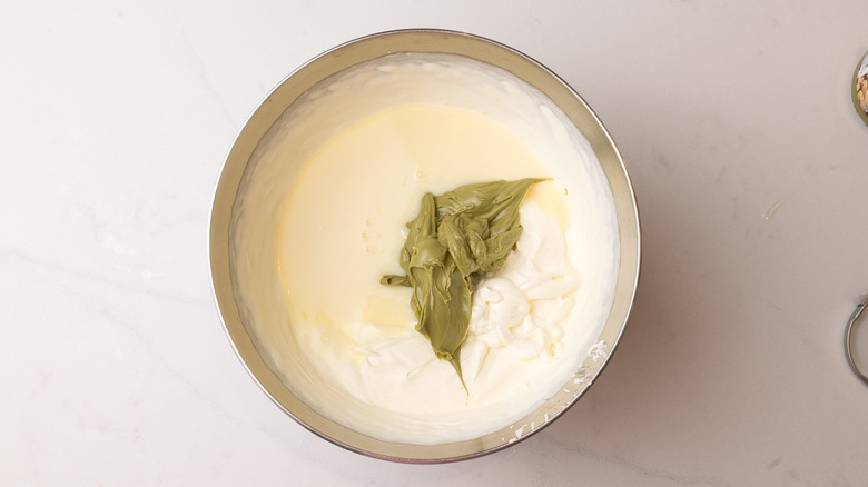 Aerial view of mixing bowl containing pistachio creme, condensed milk, and softly whipped cream