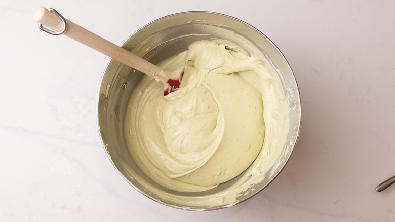 Pistachio ice cream mixture with spatula in mixing bowl
