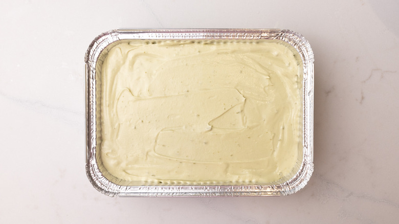 Aerial view of pistachio ice cream mixture with a smoothed out surface in foil container