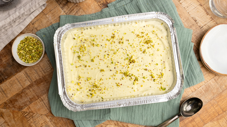 3-ingredient pistachio ice cream in a foil container next to small bowl of pistachio pieces