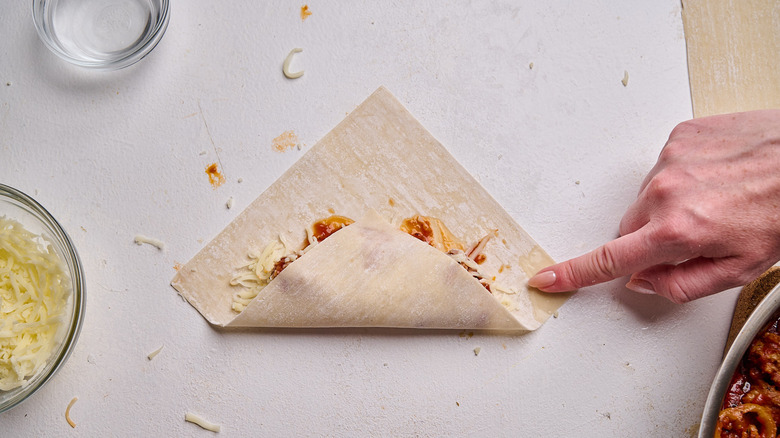 adding water to edges of egg roll wrapper