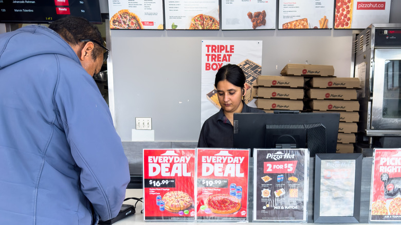A customer waiting at the counter of a Pizza Hut restaurant with employee