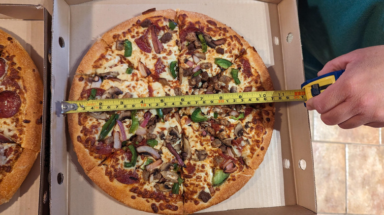measuring tape over pizza in box, close up