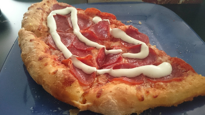 Half of a pepperoni pizza with a drizzle of creamy, white dressing on top