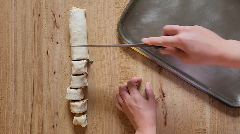 hands slicing pastry roll
