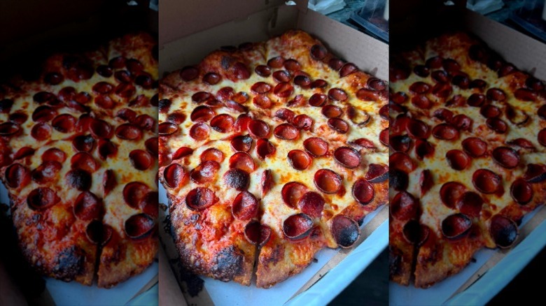 A Buffalo-style pizza sitting in a cardboard pizza box with lots of little pepperonis on top.