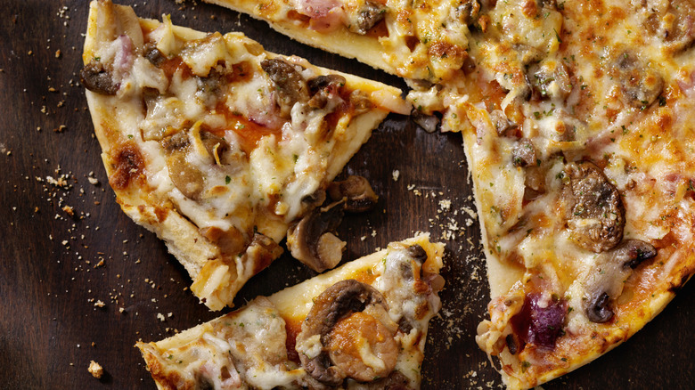 A thin pizza cut into slices on a wood board