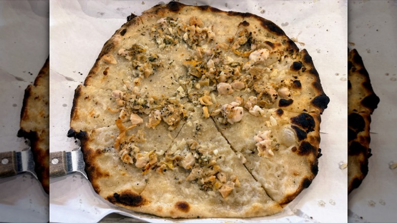 A white, New Haven-style pizza sliced on parchment paper.
