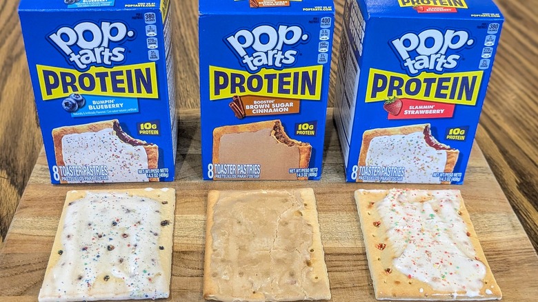 Three boxes of Pop-Tarts behind three Pop-Tarts on a wood board