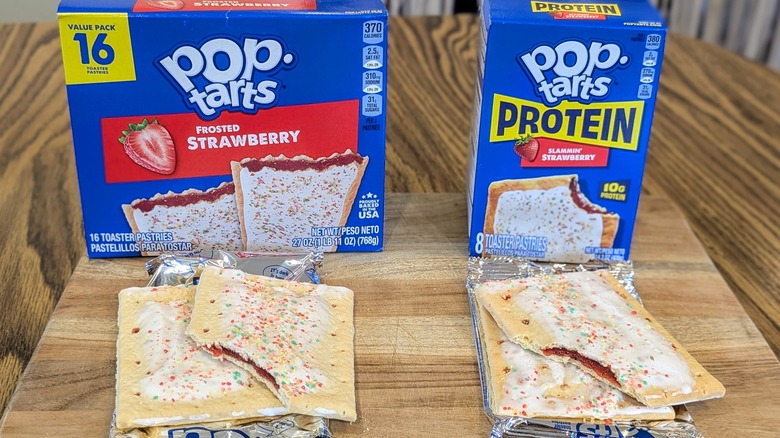 Two boxes of strawberry Pop-Tarts and two unwrapped Pop-Tarts on a wooden table
