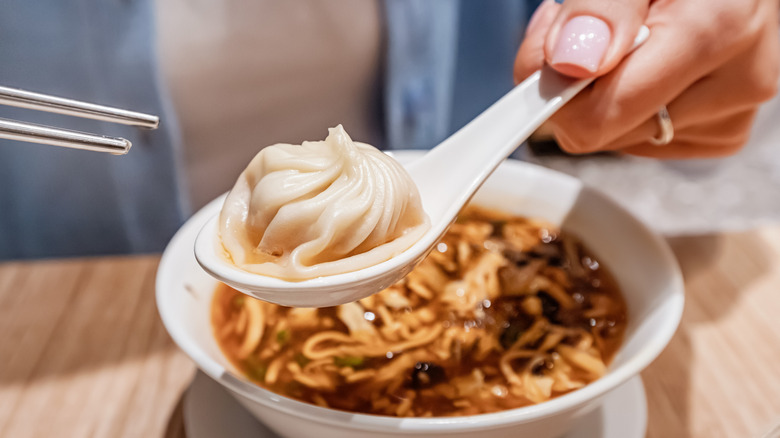 dumpling in spoon with soup in background