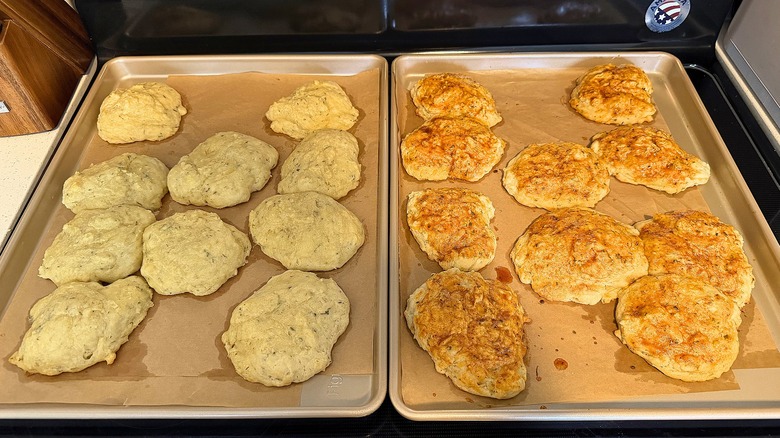 Two trays of baked Popeyes biscuits on parchment paper