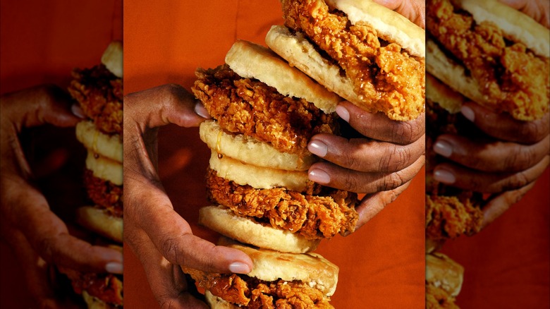close up of Popeyes Honey Chicken Biscuits stacked and held in a woman's hands