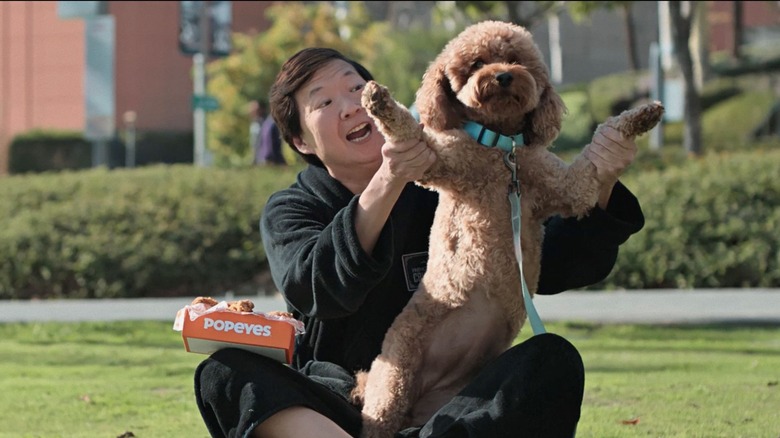 Ken Jeong holding a dog in a Popeyes television ad