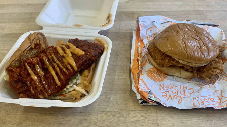 Popeyes sandwich and Dave's slider with packaging on wood background