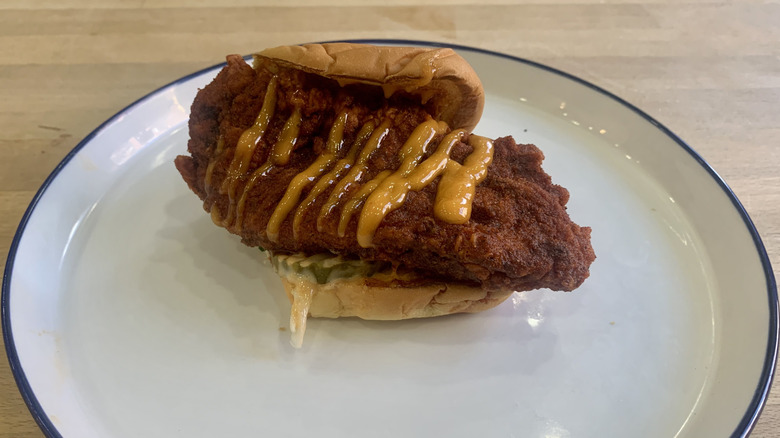 Dave's Hot Chicken slider on white plate with wood background