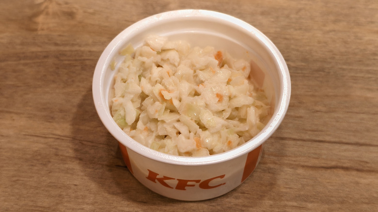 A cup of KFC coleslaw sits on a table