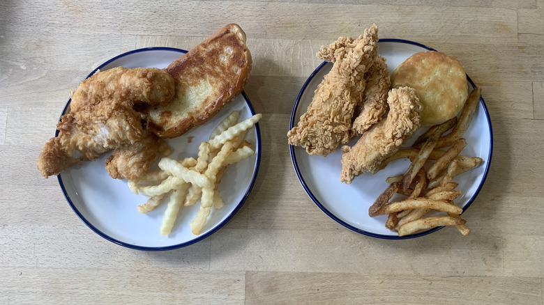 Popeyes and Raising Cane's chicken tenders meals on white plates with a wooden background