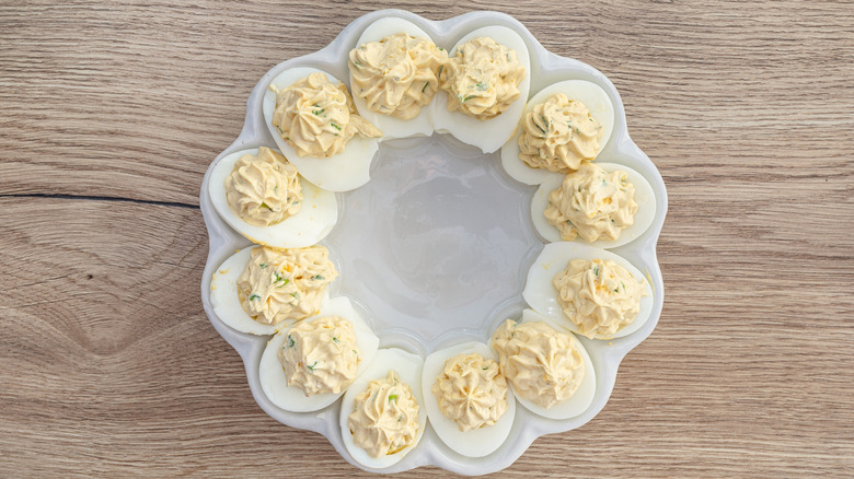 Deviled eggs arranged in a round platter on a wooden surface