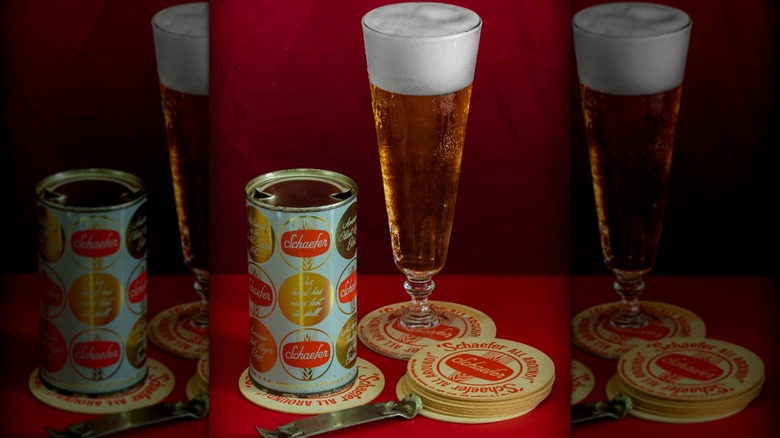 A can of F&M Schaefer beer next to a filled glass, both on coasters