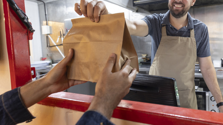 fast food employee handing bag to customer