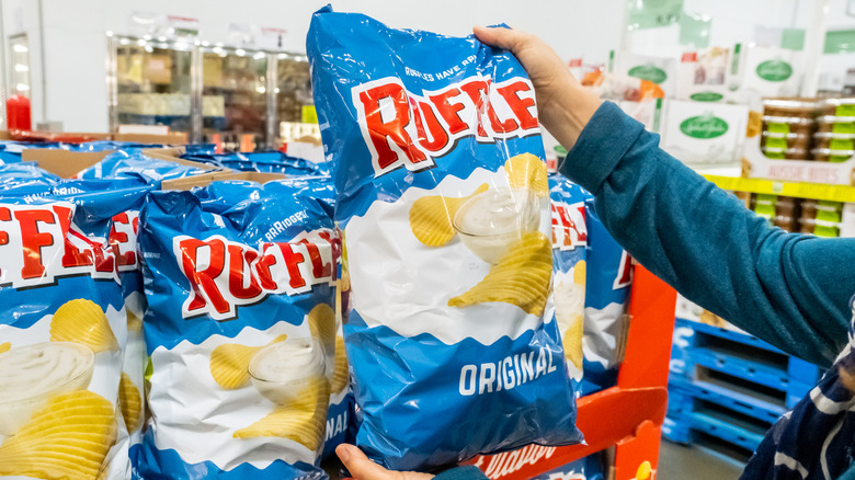 Person holding a bag of ruffles in grocery store