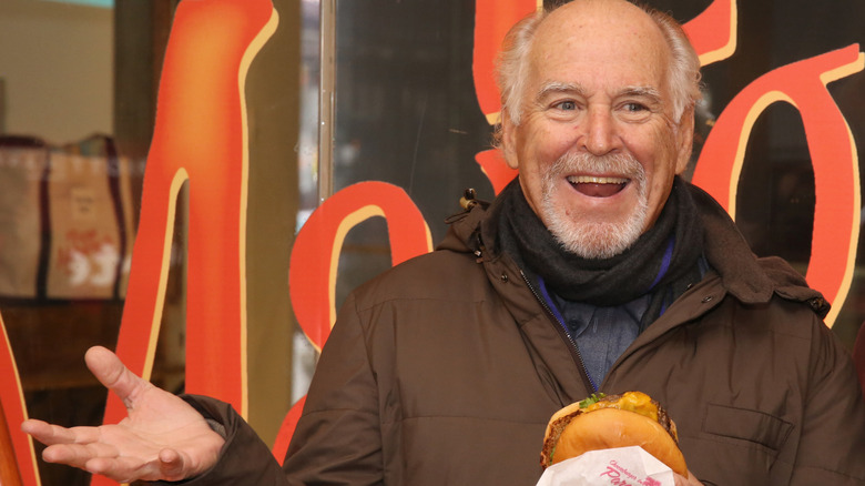 Jimmy Buffett holding a cheeseburger outside during an event