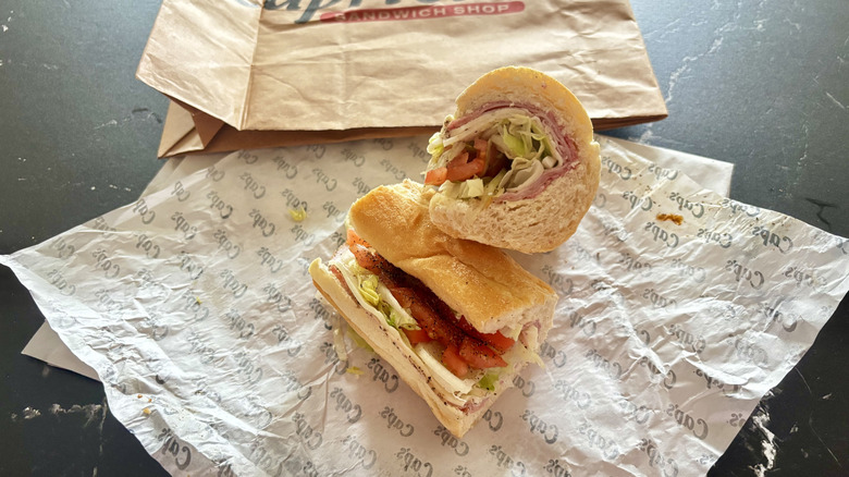Capriotti's Italian sub sandwich cut in half and displayed on wrapper with brown bag in background