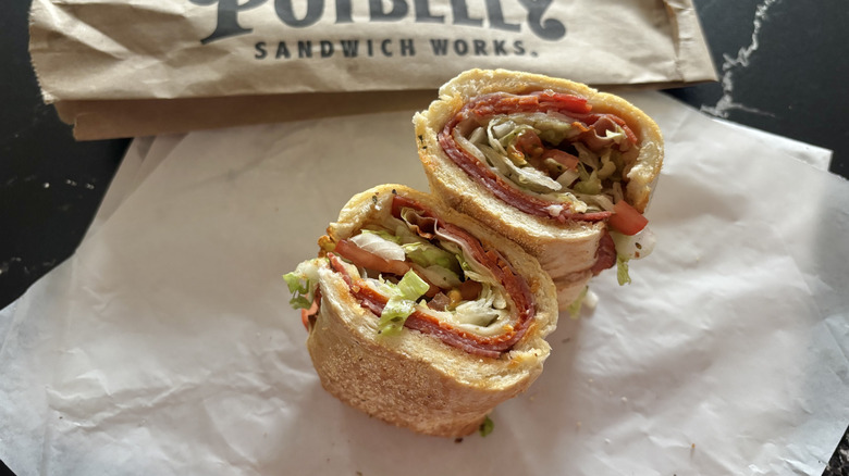Potbelly Italian sub cut in half and displayed on wrapper with brown bag in background