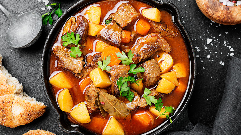 A pot roast surrounded by bread, ladle
