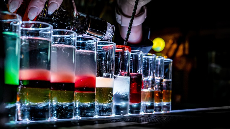 Bartender creating some colorful layered drinks