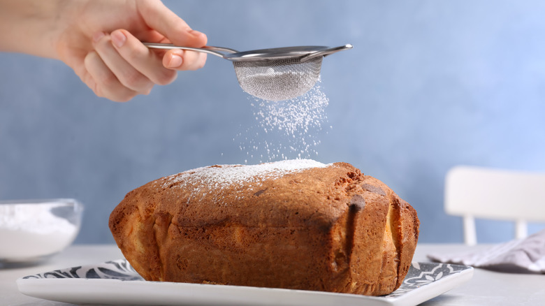 sifting powdered sugar onto cake