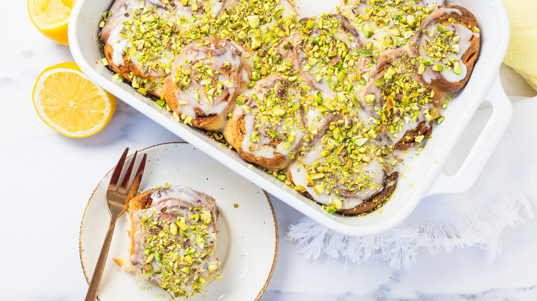 Preserved lemon cinnamon buns in white baking dish with one taken out.