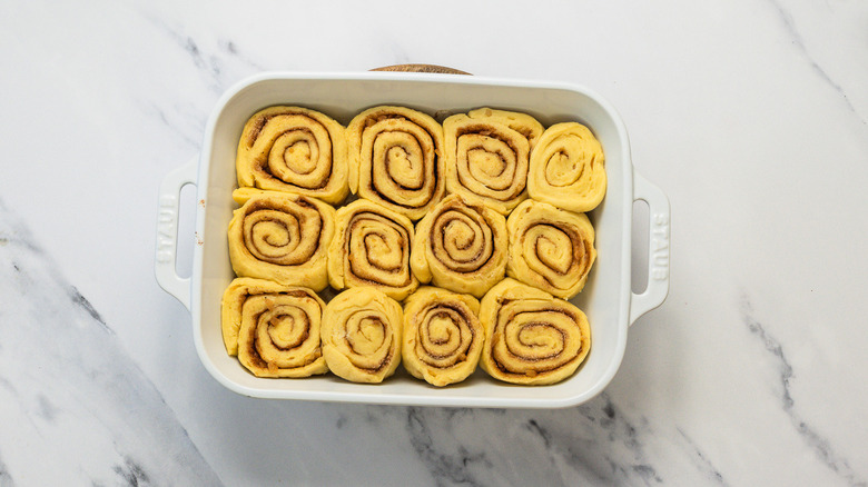 Raw cinnamon buns in white dish.