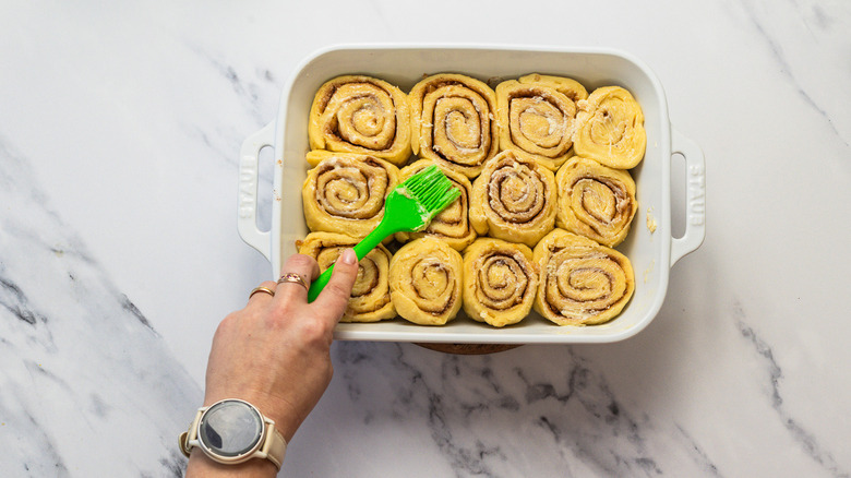 Brushing cinnamon buns with butter.
