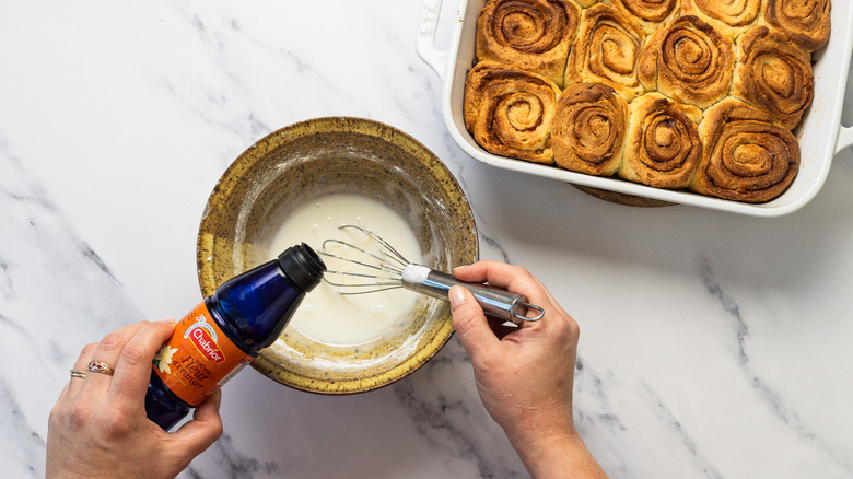Adding orange blssom water to whisked lemon cinnamon bun icing.