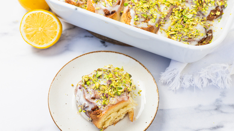 Preserved lemon cinnamon buns in white baking dish with one taken out.