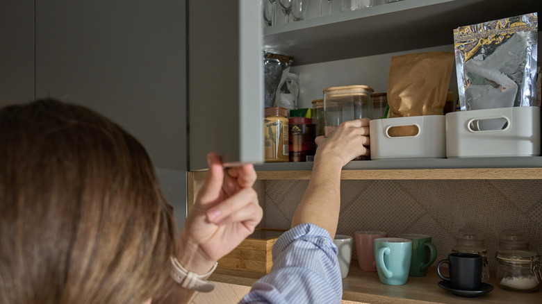 Person reaching for containers in pantry